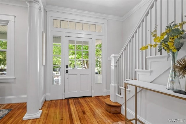 entryway with stairway, light wood-type flooring, crown molding, baseboards, and decorative columns