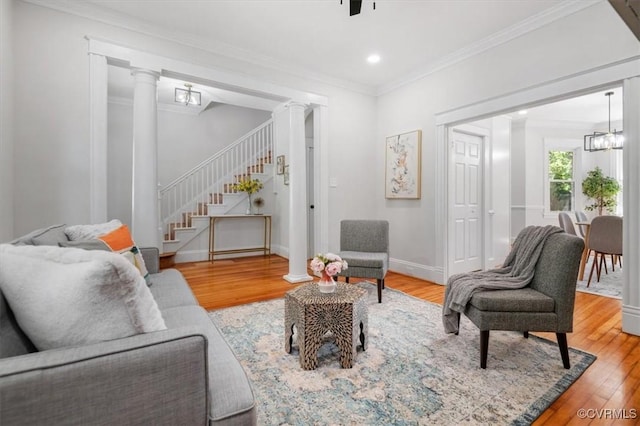 living room featuring decorative columns, light wood-style flooring, ornamental molding, stairway, and recessed lighting