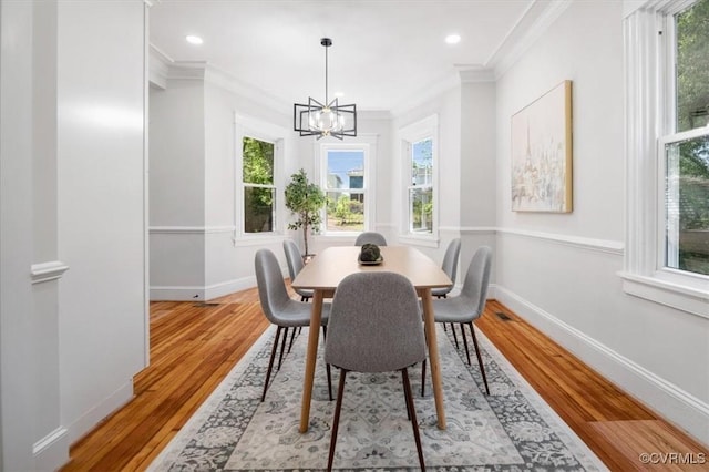 dining room with a chandelier, plenty of natural light, ornamental molding, light wood-style floors, and baseboards