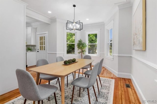 dining space featuring a chandelier, crown molding, light wood-style flooring, baseboards, and recessed lighting