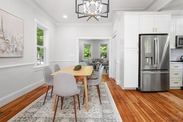 dining space featuring healthy amount of natural light, light wood-style floors, ornamental molding, a chandelier, and baseboards
