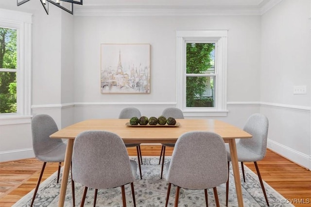 dining room with healthy amount of natural light, ornamental molding, baseboards, and light wood-style flooring