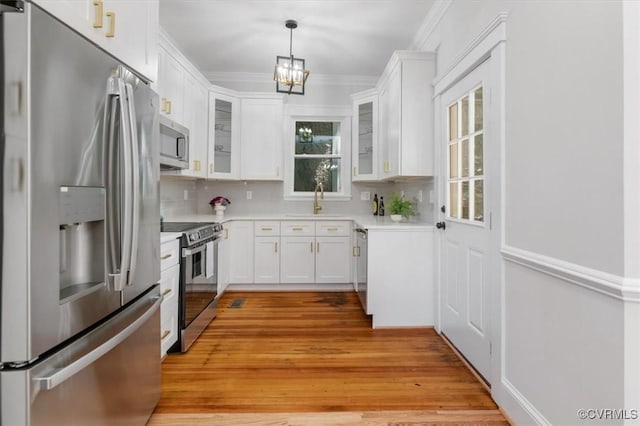 kitchen with appliances with stainless steel finishes, white cabinetry, decorative backsplash, and crown molding