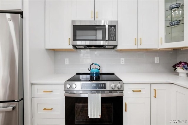 kitchen with stainless steel appliances, light countertops, white cabinets, and decorative backsplash