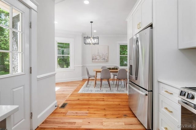 kitchen with appliances with stainless steel finishes, a chandelier, light wood-type flooring, white cabinetry, and recessed lighting