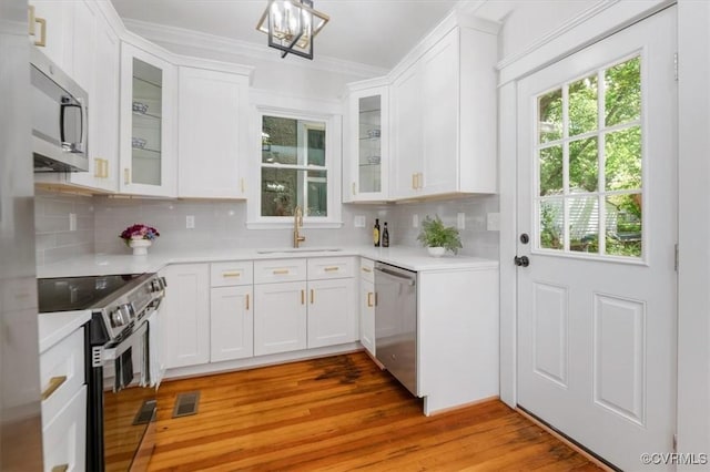 kitchen with appliances with stainless steel finishes, a sink, light countertops, decorative backsplash, and white cabinets