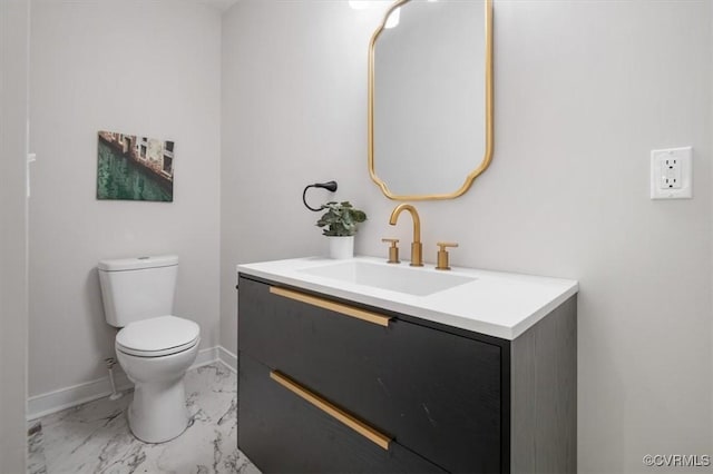 bathroom featuring toilet, vanity, marble finish flooring, and baseboards