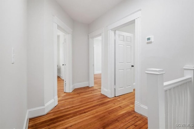 hall featuring light wood-style flooring and baseboards