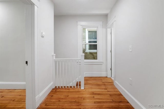 hall featuring an upstairs landing, light wood finished floors, and baseboards