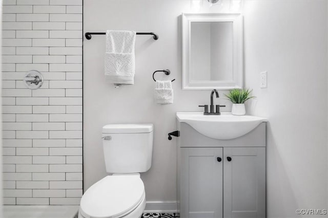 full bath featuring toilet, vanity, and tiled shower