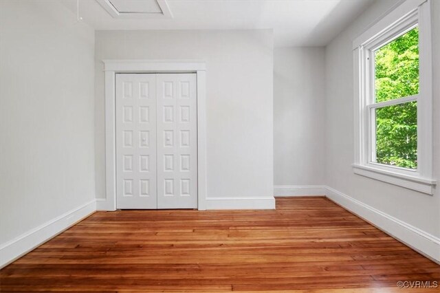 unfurnished bedroom featuring light wood-type flooring, a closet, and baseboards