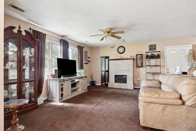 living room with dark colored carpet, ceiling fan, baseboards, a textured ceiling, and a tile fireplace
