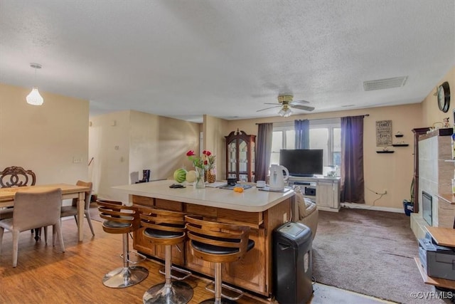 kitchen featuring a textured ceiling, light countertops, ceiling fan, a center island, and baseboards