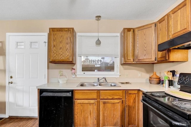 kitchen with black appliances, a sink, light countertops, under cabinet range hood, and a textured ceiling