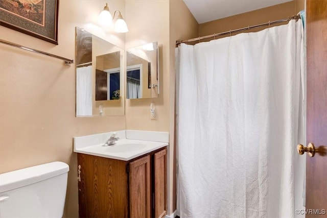bathroom featuring toilet, vanity, and a shower with curtain