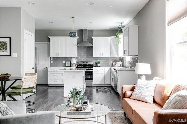 kitchen with stainless steel gas range, wall chimney range hood, light countertops, a center island, and open floor plan