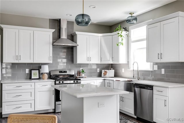 kitchen featuring stainless steel appliances, wall chimney exhaust hood, a sink, white cabinets, and recessed lighting