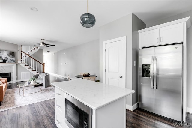 kitchen featuring stainless steel appliances, dark wood-style floors, white cabinets, a center island, and a high end fireplace
