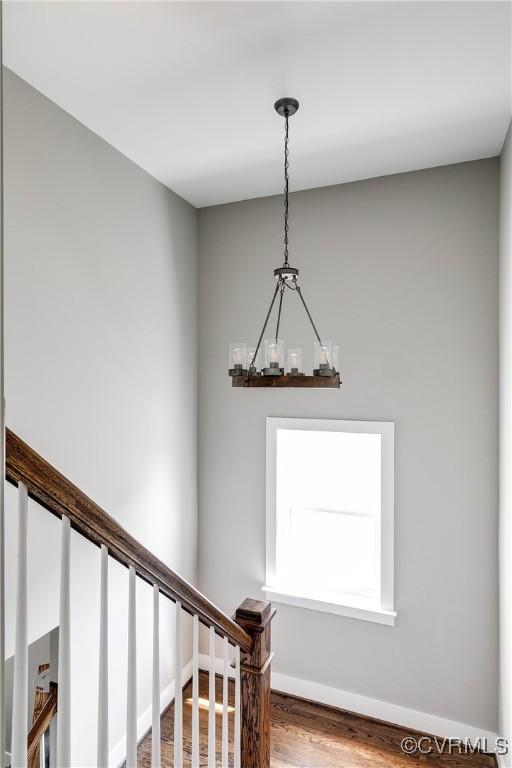 stairway featuring wood finished floors, a chandelier, and baseboards