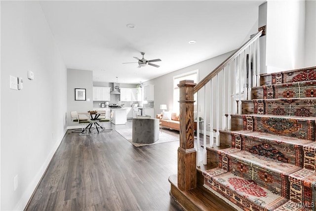 staircase featuring a ceiling fan, wood finished floors, and baseboards