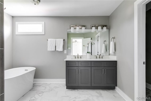 full bathroom with marble finish floors, baseboards, a freestanding bath, double vanity, and a ceiling fan