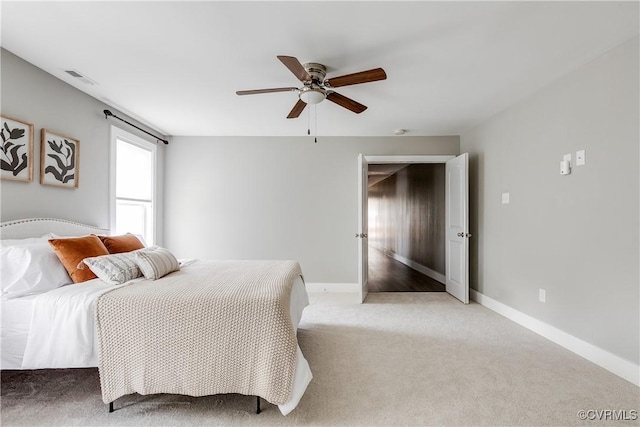 bedroom featuring light carpet, baseboards, and ceiling fan
