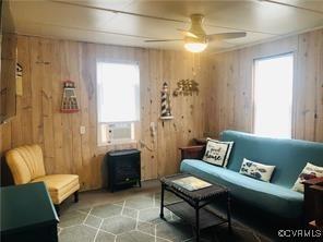 41 Hobday St, Mathews, VA 23128 - living area featuring plenty of natural light, wood walls, ceiling fan, and a wood stove