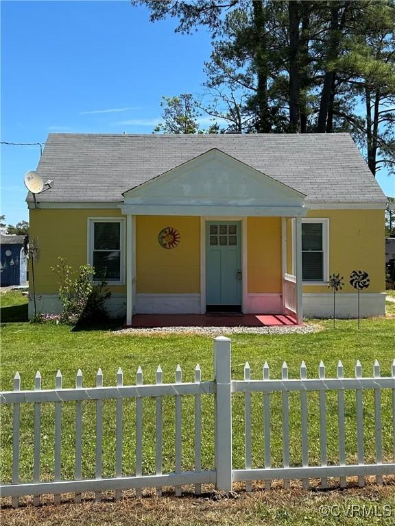 41 Hobday St, Mathews, VA 23128 - view of front facade with a fenced front yard, a shingled roof, and stucco siding