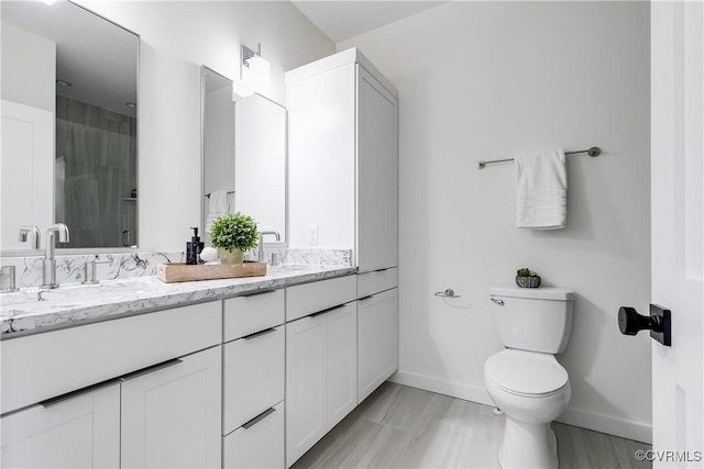 bathroom with baseboards, toilet, a shower stall, and double vanity