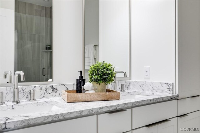 bathroom featuring a shower stall and double vanity