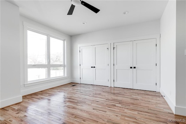 unfurnished bedroom with two closets, light wood-type flooring, baseboards, ceiling fan, and recessed lighting