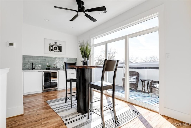 dining area featuring beverage cooler, light wood-style floors, and a ceiling fan