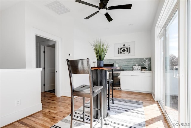 dining space with ceiling fan, light wood finished floors, wine cooler, baseboards, and recessed lighting