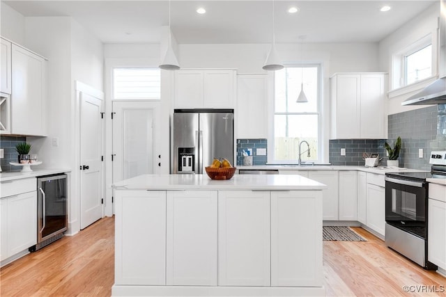kitchen featuring appliances with stainless steel finishes, beverage cooler, tasteful backsplash, a center island, and white cabinetry