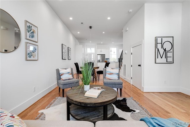living area featuring baseboards, light wood-style floors, and recessed lighting