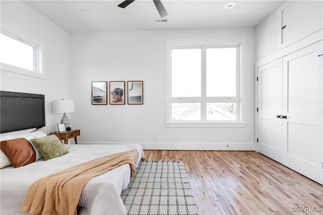 bedroom with light wood-style floors, baseboards, and ceiling fan