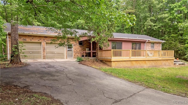ranch-style home featuring asphalt driveway, an attached garage, brick siding, and a deck