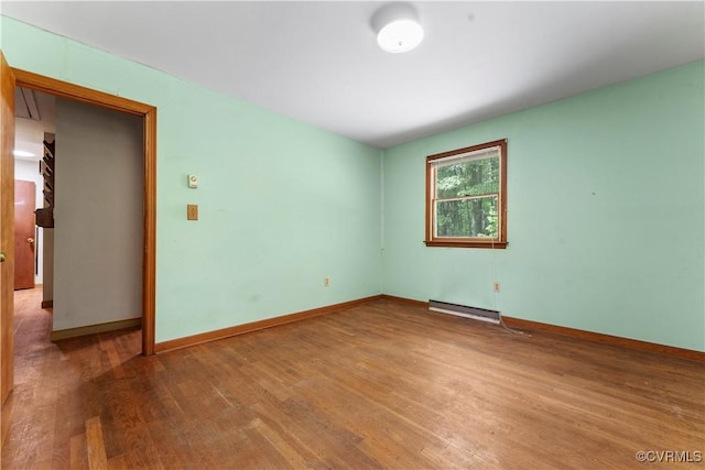 empty room featuring wood finished floors, a baseboard radiator, and baseboards