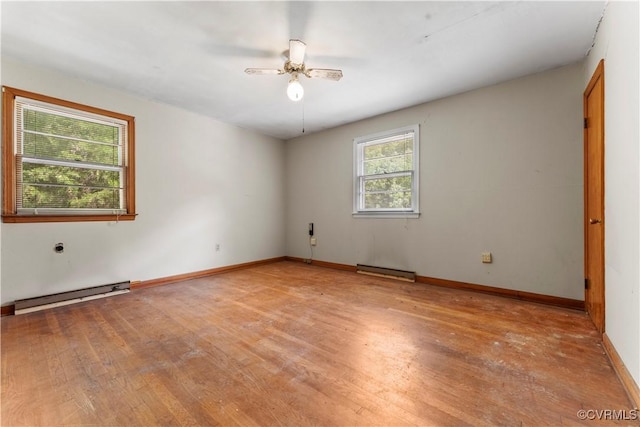 empty room with a baseboard heating unit, light wood finished floors, ceiling fan, and baseboards