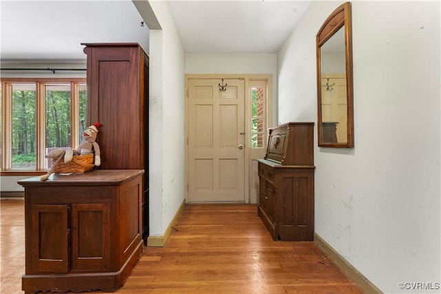 doorway with light wood-style flooring and baseboards