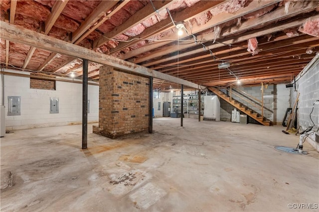 unfinished below grade area with stairway, electric panel, water heater, and freestanding refrigerator