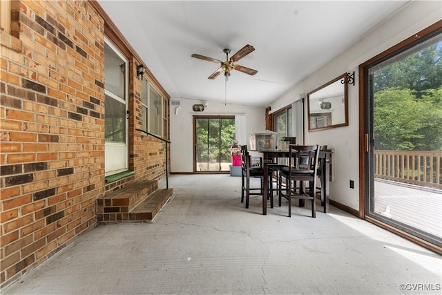 sunroom / solarium featuring brick wall, lofted ceiling, and baseboards