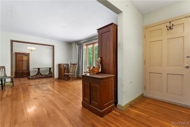 entrance foyer featuring light wood finished floors, a chandelier, and baseboards
