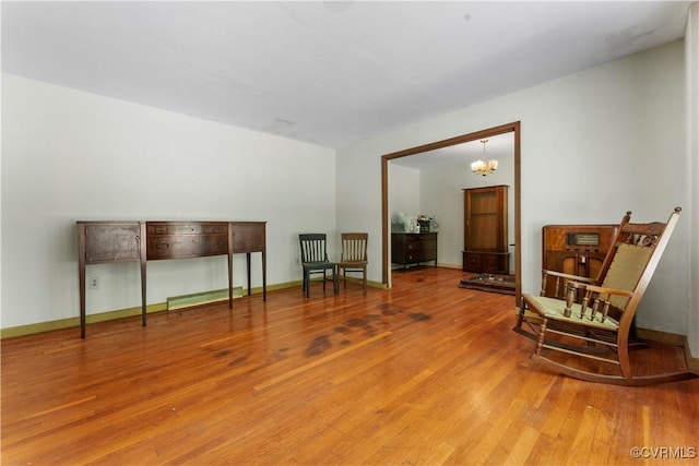 living area featuring wood finished floors, a chandelier, and baseboards
