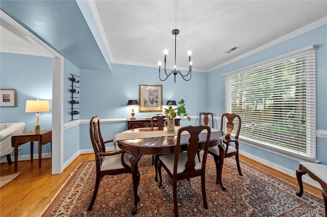dining space featuring light wood finished floors, a chandelier, ornamental molding, and baseboards