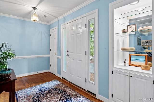 foyer entrance featuring wood finished floors, crown molding, and baseboards