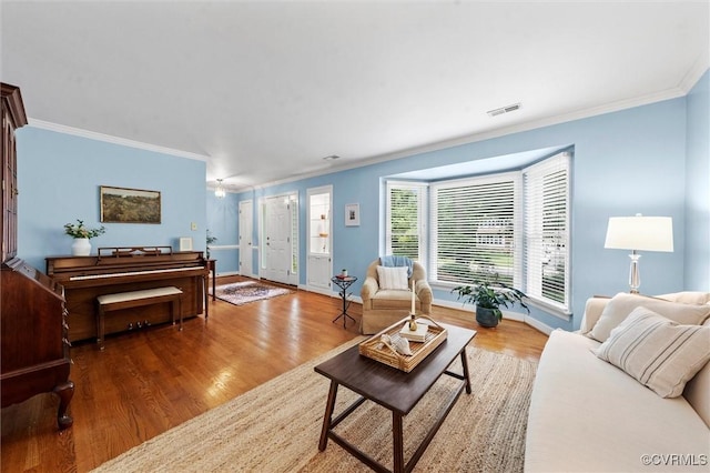 living area with crown molding, wood finished floors, and baseboards