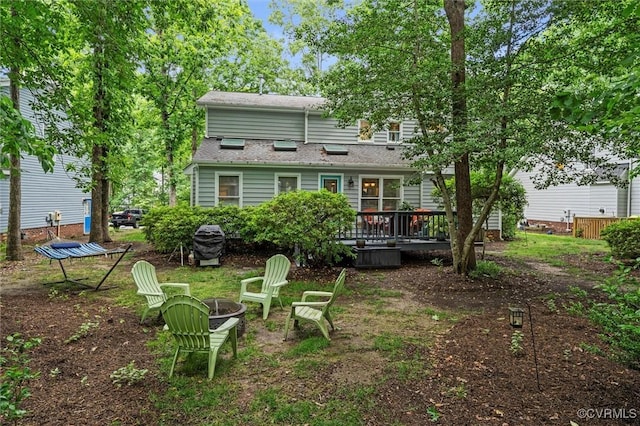 back of property with a deck and a fire pit
