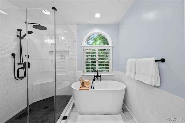 bathroom featuring a freestanding tub, tile walls, a stall shower, a wainscoted wall, and marble finish floors