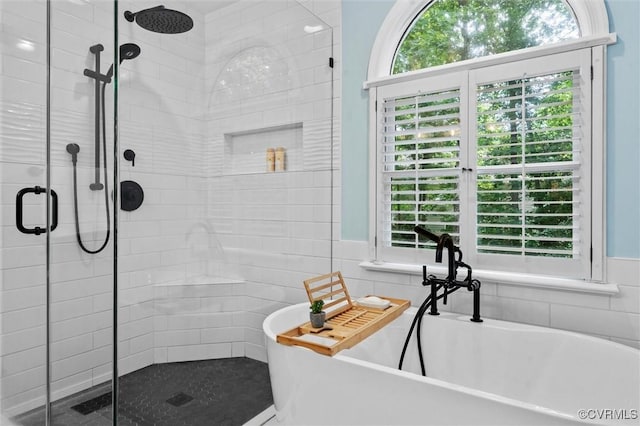 full bath featuring a stall shower, tile walls, and a freestanding bath
